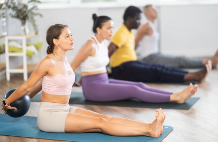 Young woman doing pilates with soft ball in groupの写真素材