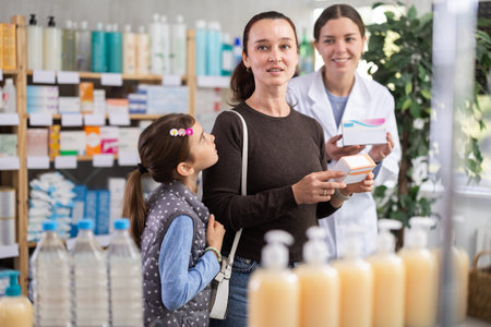 Mother choosing vitamins for daughter while pharmacist suggesting optionsの写真素材