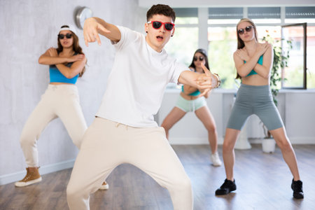 Group of young women and young guy in sunglasses dancing hip hop