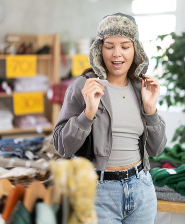 Young woman tries on fur hat in clothing store