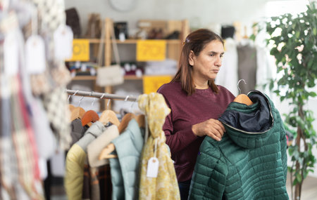 During November sales, Latin woman choose down coat, other client in backgroundの写真素材