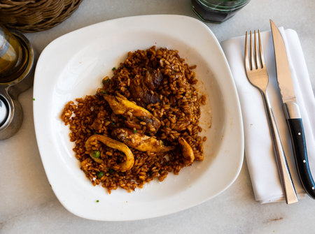 Plate is filled with paella made according to Spanish recipe from rice cereals, seafood, and chicken