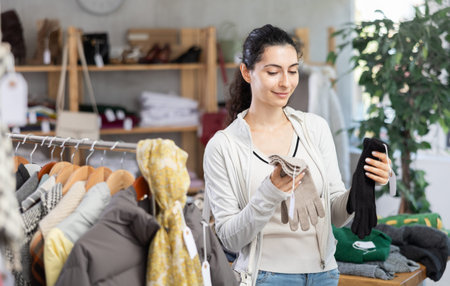 Young woman choosing gloves in clothing store