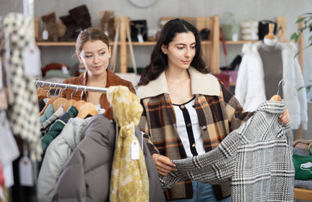 Two young women choosing outerwear in storeの写真素材