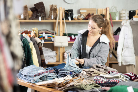 Female shopper chooses a jeans trousers in clothing storeの写真素材