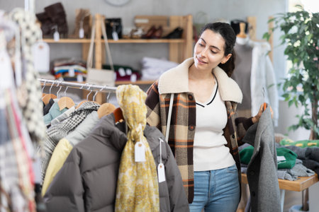Young woman choosing coat in clothing storeの写真素材