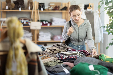 Girl near showcase examine goods, buying ladys jumper.