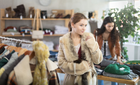 Young woman trying on fur coat in storeの写真素材