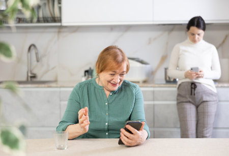 Portrait of a happy mature woman reading messages on her mobileの写真素材