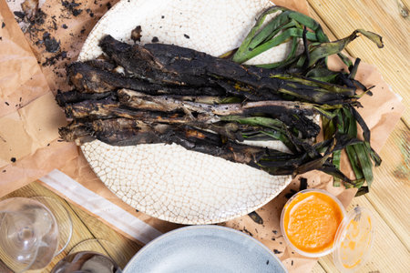 On round plate - fried sweet green onions kalsot, supplemented with jar of romesco sauce,red wineの写真素材