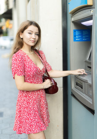 Young woman carefully entering pin code at atmの写真素材