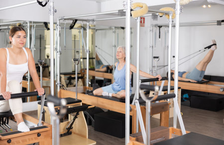 Young girl doing exercises on reformer in pilates studio