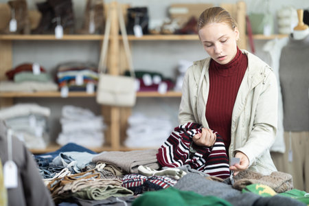 Selective teen girl choosing sweater in clothing storeの写真素材