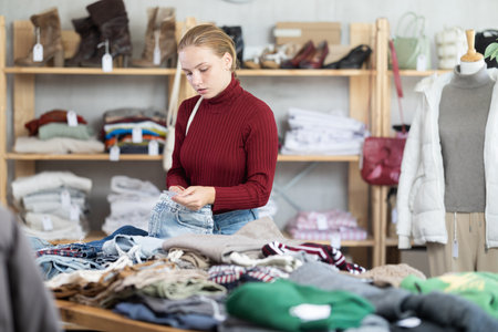 While shopping, teen girl browsing goods items and choose elect denim trousers in storeの写真素材