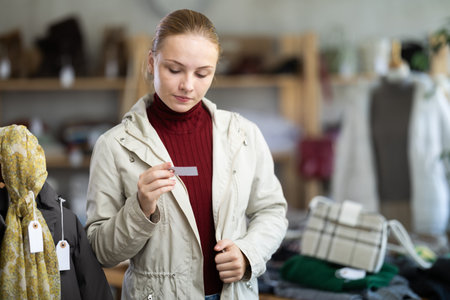Selective teenage girl trying on beige jacket in clothing storeの写真素材