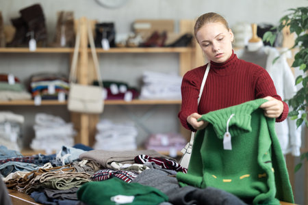 Selective teen girl choosing sweater in clothing storeの写真素材