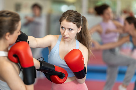 Female co-participant and woman sparring partners during training battle fight using technique of boxing match in sport gymの写真素材