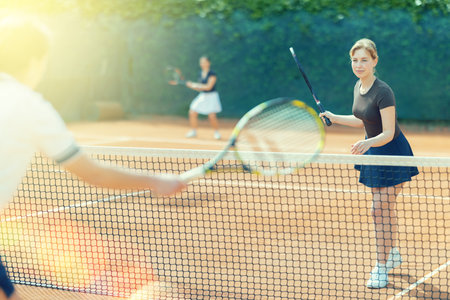Young woman playing doubles tennis on courtの写真素材