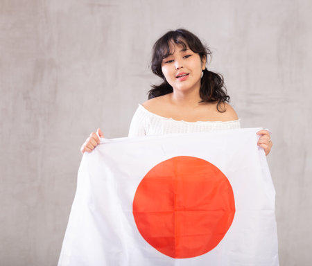 Smiling young girl holding Japan flagの写真素材
