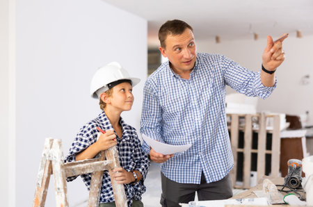 Father and his young son discussing work plan in construction siteの写真素材