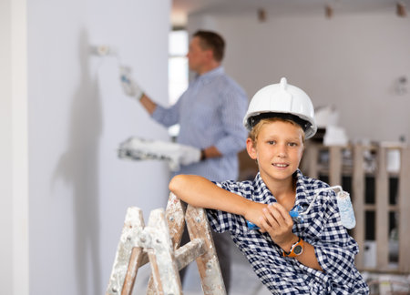 Portrait of cheerful boy with paint roller in construction siteの写真素材