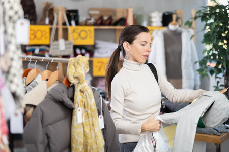 Adult woman choosing down jacket in clothing storeの写真素材