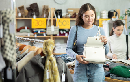 Happy girl chooses fashionable bag in clothing storeの写真素材