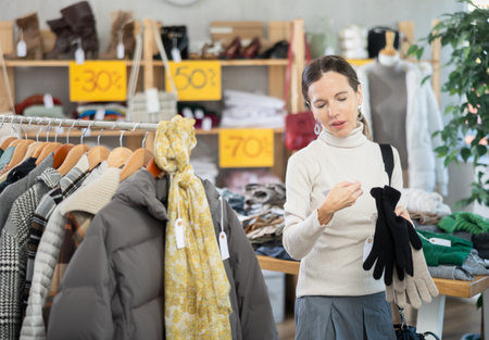 Woman carefully selects warm winter gloves in clothing storeの写真素材