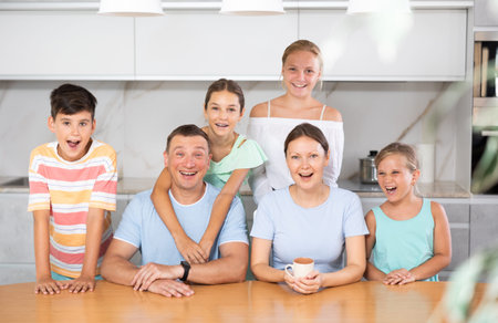 Portrait of happy family - father and mother with four children at table at home