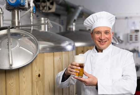Happy brewery owner inviting to tasting amber beer