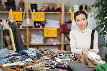 Adult woman chooses sweater in clothing store