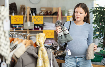 Pregnant woman choosing hat in clothing storeの写真素材