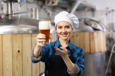 Portrait of positive woman brewmaster with glass of beerの写真素材