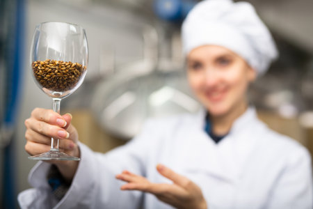 Positive female brewer with glass filled with barleyの写真素材