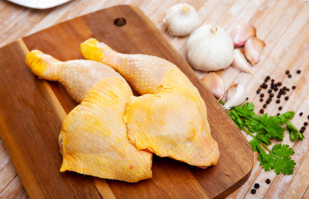 Raw chicken leg quarters with garlic, greens and spicesの写真素材