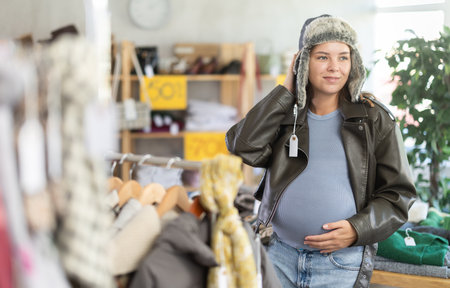 Pregnant woman tries on fur hat in clothing storeの写真素材