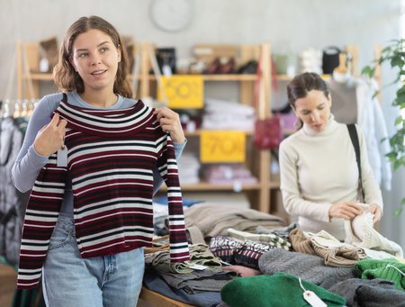 Young woman choosing sweater in clothing storeの写真素材