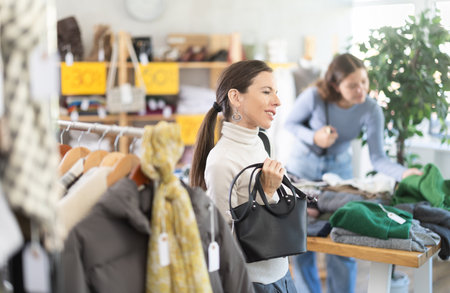 Woman chooses fashionable handbag in clothing boutiqueの写真素材
