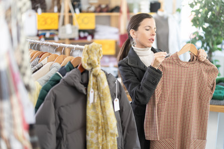 Adult woman chooses warm dress in clothing storeの写真素材