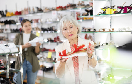 Mature woman who came to shoe store for shopping, chooses summer shoesの写真素材