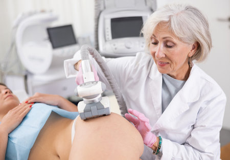 Old woman specialist doing massage of hips of young womanの写真素材