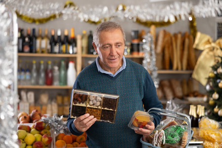 Elderly man chooses dried fruits and fruit jelly at grocery store