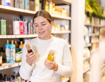 Young female client buys skin care product for face and body, chooses oil texture emulsionの写真素材