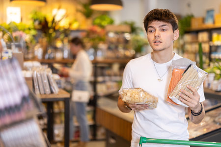 Store visitor, guy in sales area choosing pastaの写真素材