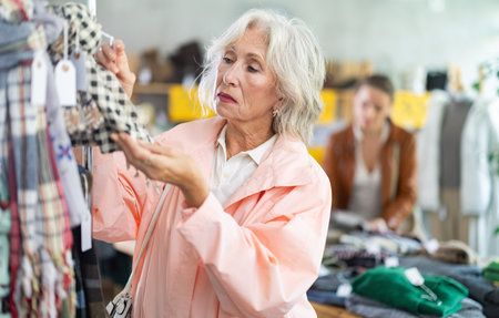Elderly woman chooses scarf in clothing storeの写真素材