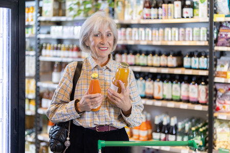 Mature woman chooses natural fruit juiceの写真素材
