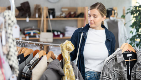 Adult woman chooses coat in clothing storeの写真素材