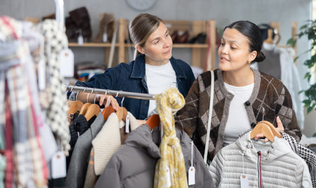 Two women friends browsing goods items and choose elect something autumn outwearの写真素材