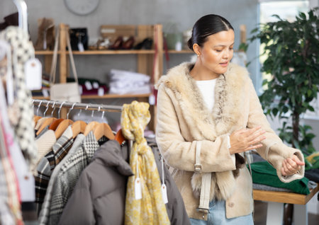 Adult woman trying on fur coat in storeの写真素材