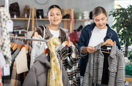 Two women friends browsing goods items and choose elect something autumn outwearの写真素材